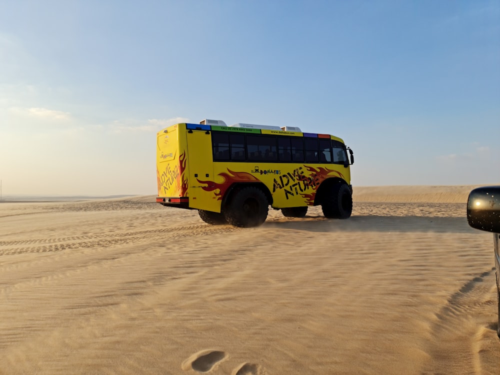 a yellow bus driving down a sandy road
