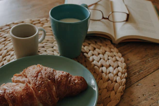 a blue plate topped with croissants next to a cup of coffee