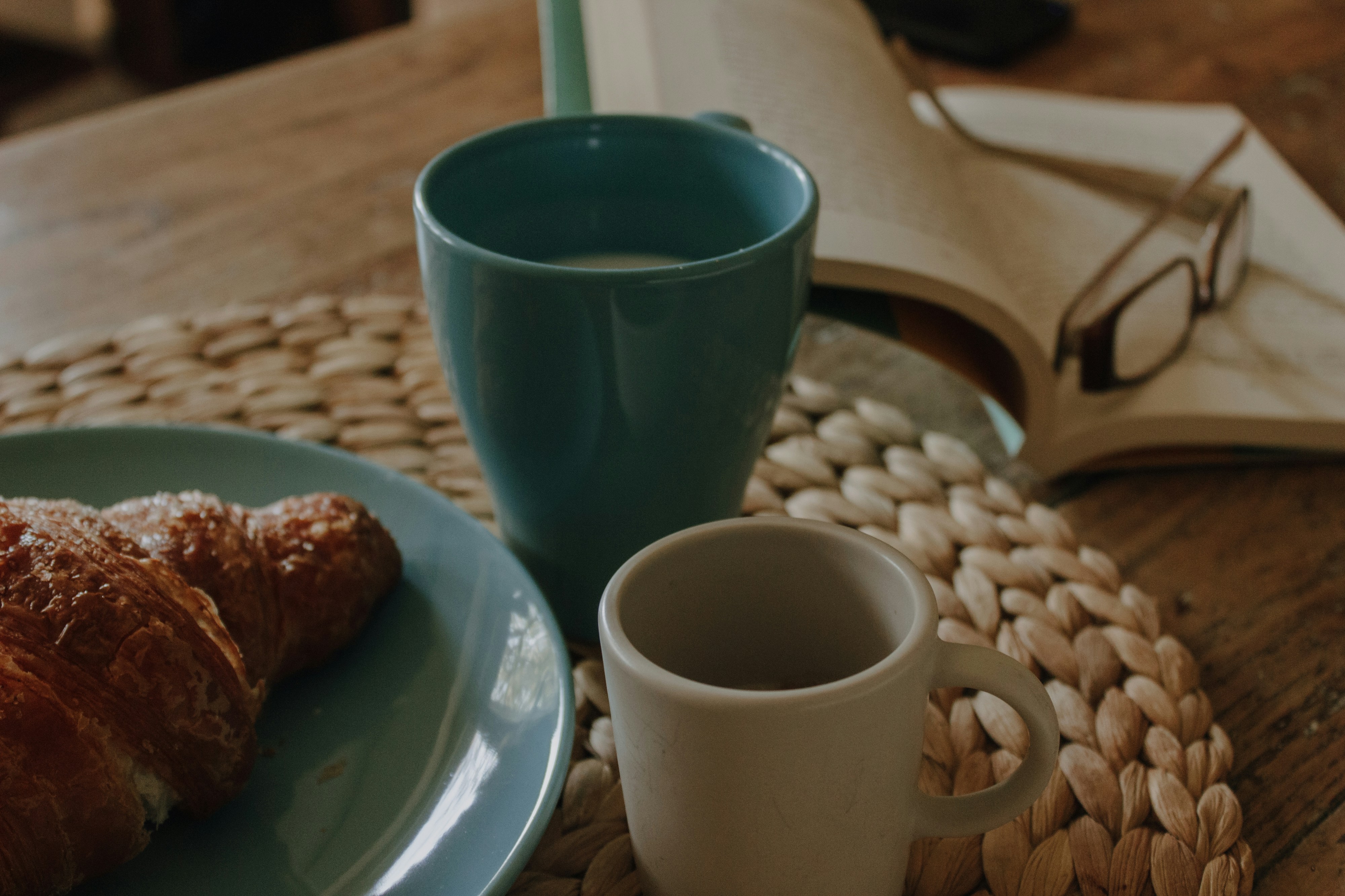 a cup of coffee and a croissant on a table