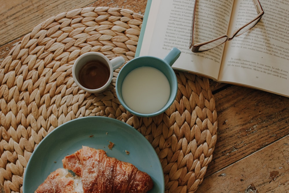 a cup of coffee and a croissant on a table