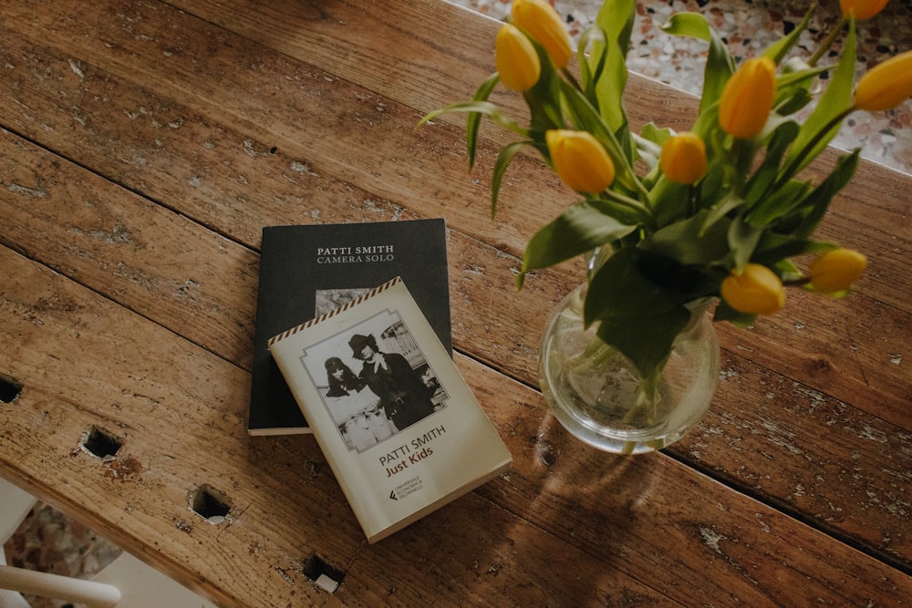 a vase filled with yellow flowers next to a book