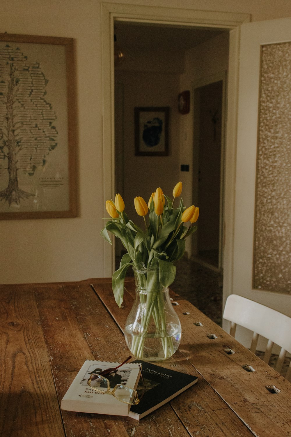 a vase of yellow tulips sitting on a wooden table