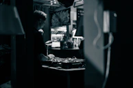 A smiling DJ wearing headphones in a warmly lit home studio.