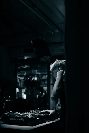 Close-up of a DJ mixing tracks with a focused expression in a lively club setting.