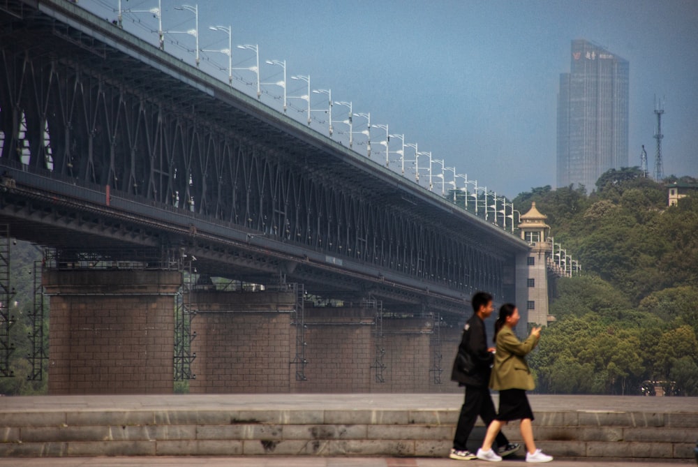 a couple of people walking across a bridge