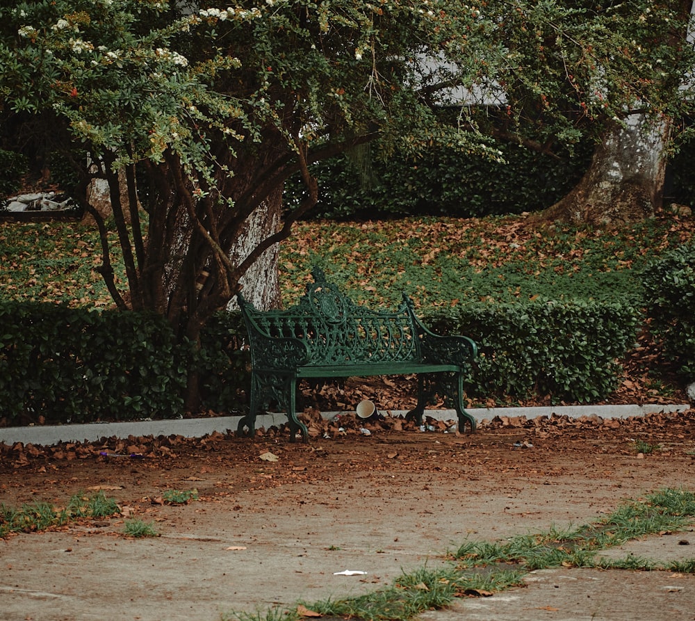 a green park bench sitting next to a tree
