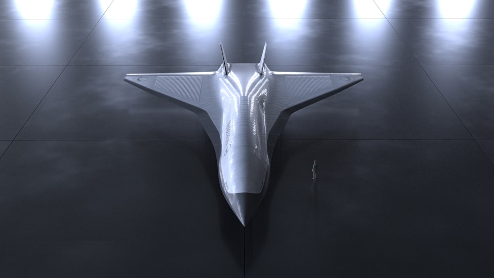 a silver fighter jet sitting on top of a black floor