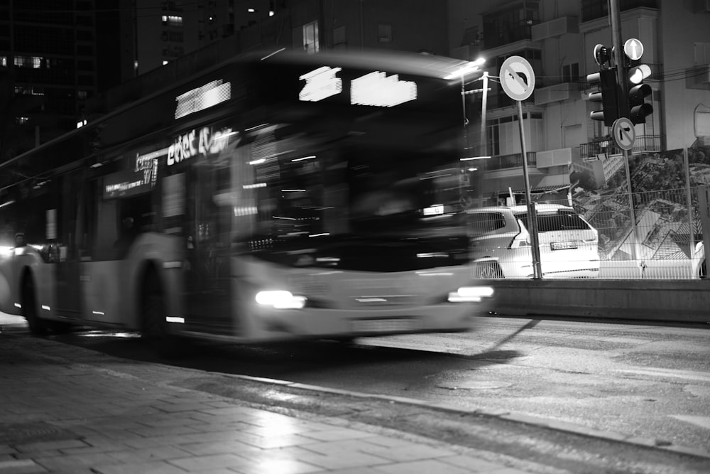 a black and white photo of a bus driving down the street