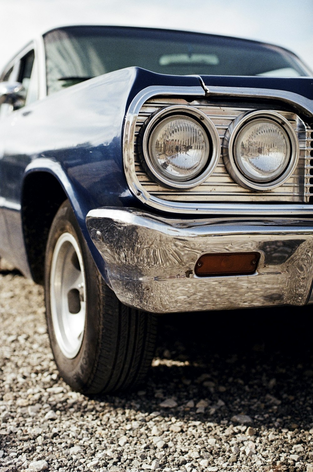 the front end of a car parked on a gravel road