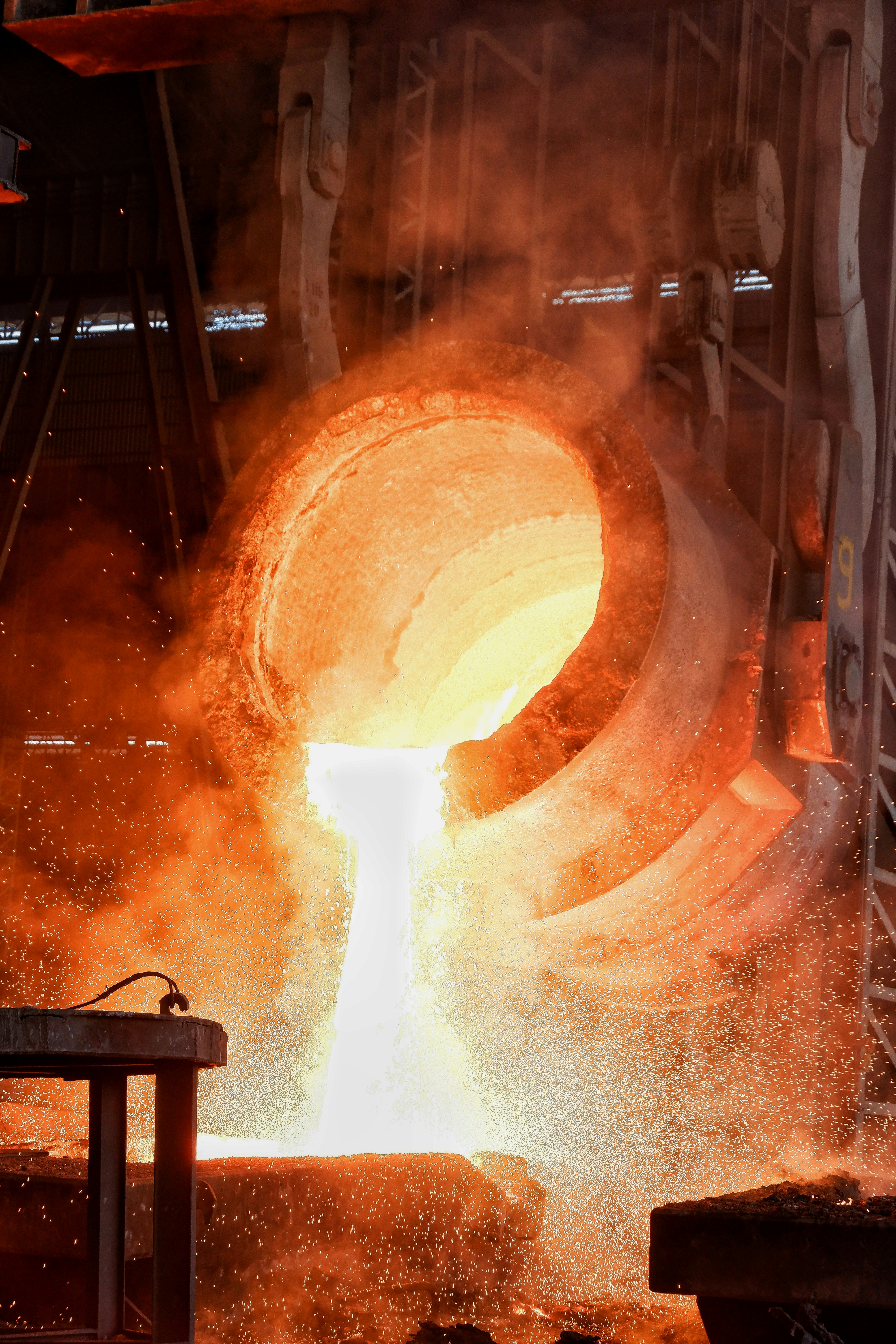 Steel factory interior with molten metal glow, industrial orange light, dark smoky atmosphere, dramatic industrial scene
