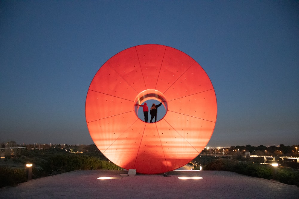 un grand objet rouge avec un couple debout à l’intérieur