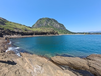 A serene view of Jeju Island's coastal cliffs under a clear blue sky.