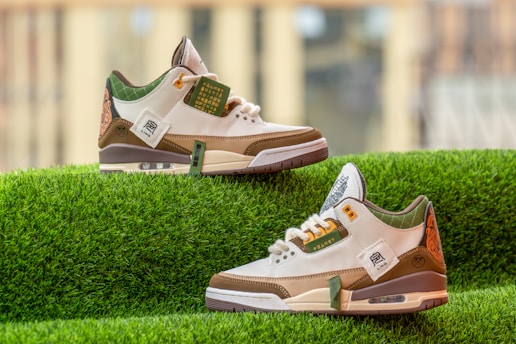 A pair of stylish sneakers with white, brown, and green accents is displayed on a vibrant green grass-like surface. The sneakers feature intricate designs on the heel and various labels and text on the side. The background is softly blurred, emphasizing the sneakers.
