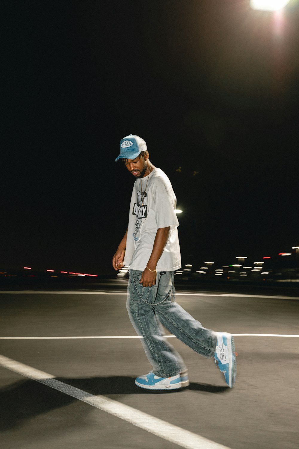 a man walking across a parking lot at night