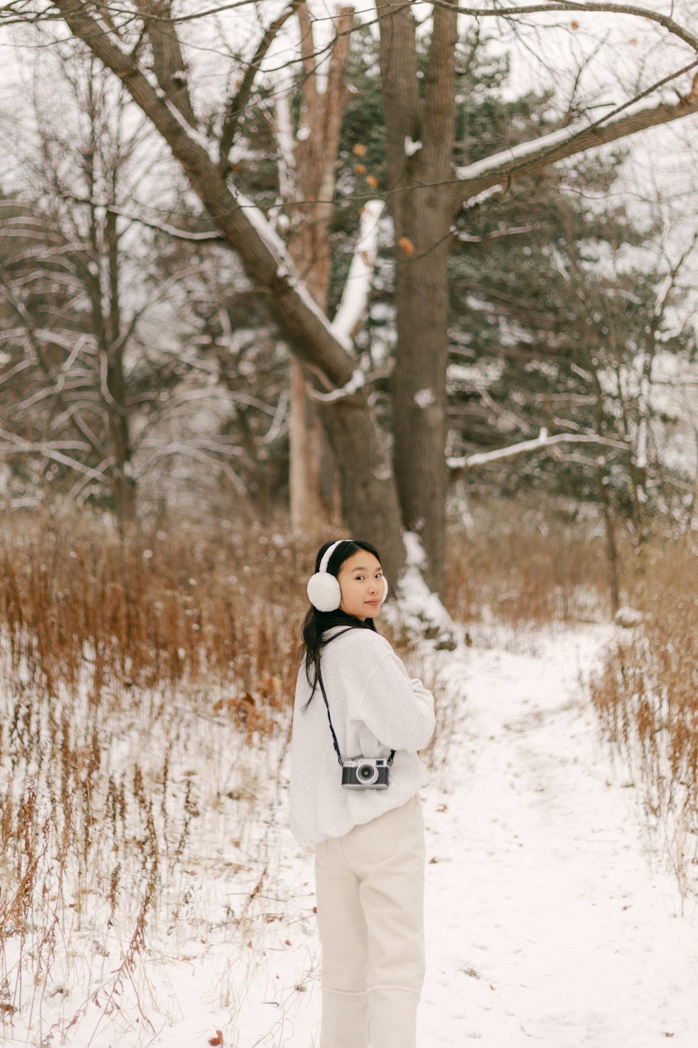 a woman standing in the snow with her headphones on