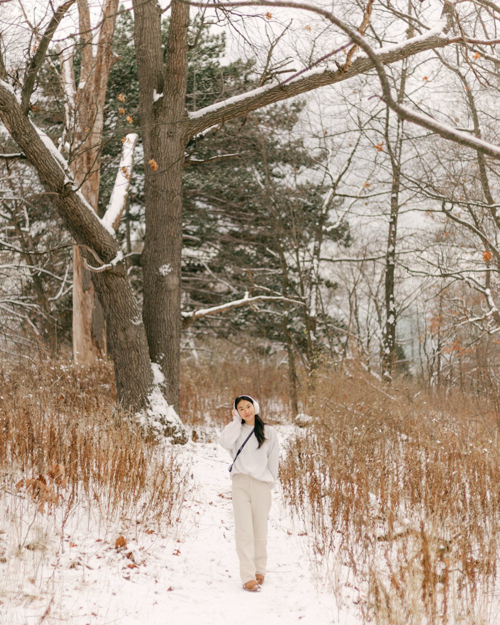 a woman walking through a snow covered forest