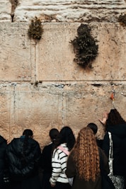 A close-up photo of a handwritten note being gently placed into the crevices of the Western Wall.