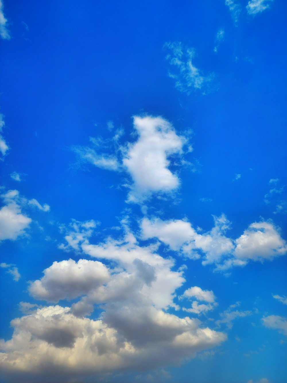 a blue sky with white clouds and a plane in the foreground