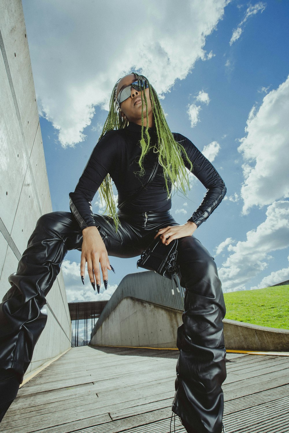 a woman with green hair wearing black leather pants