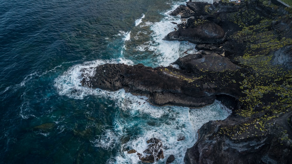 an aerial view of the ocean and rocky coastline