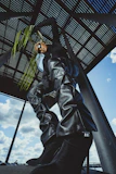 Model wearing a dark grey oversized t-shirt with metallic silver details in a futuristic urban setting.
