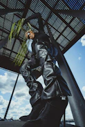 Model wearing a dark grey oversized t-shirt with metallic silver details in a futuristic urban setting.