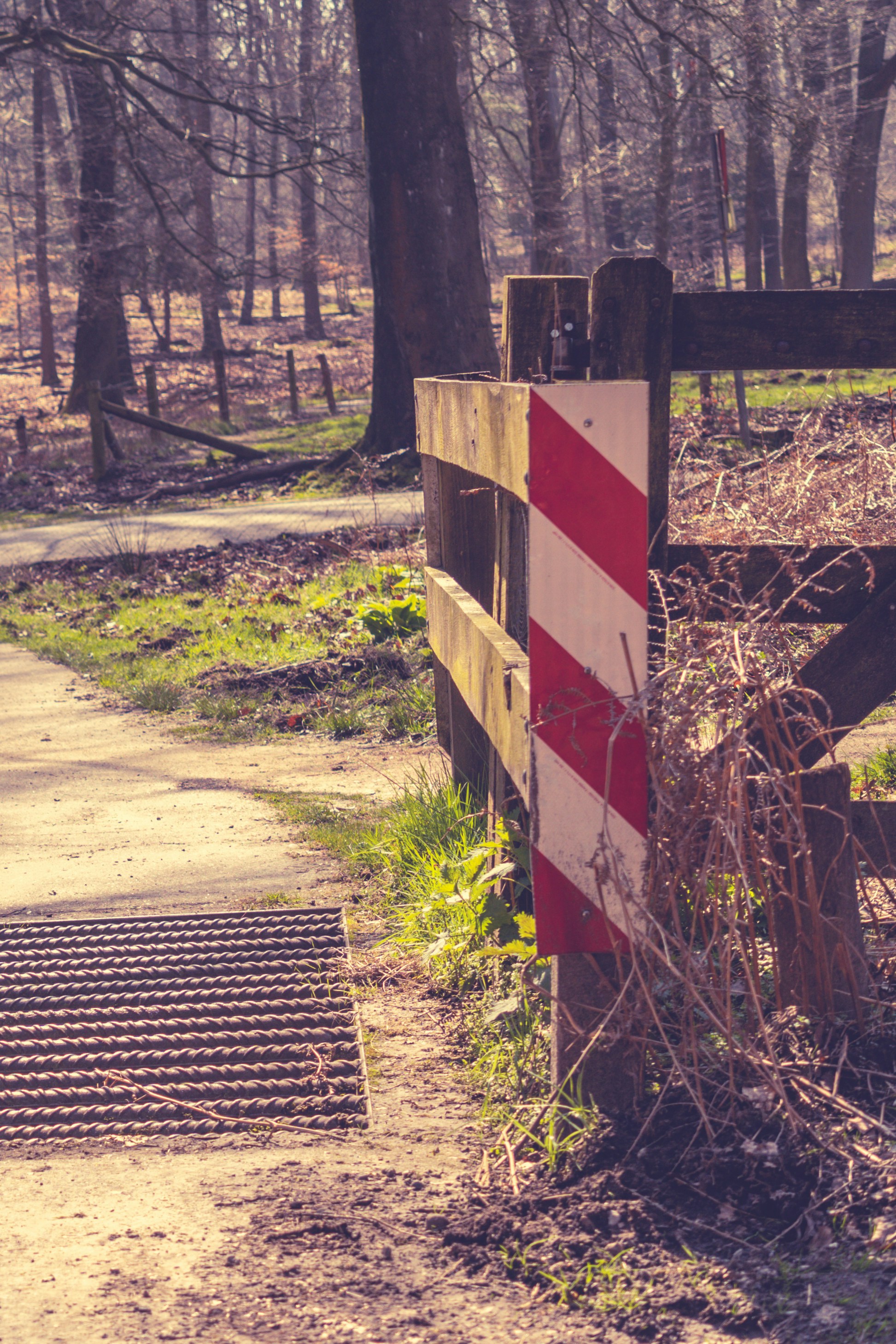a red and white striped sign sitting next to a wooden fence