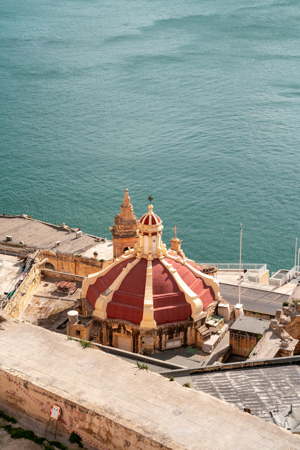 a large building with a red and white roof next to a body of water