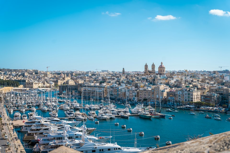 The Grand Harbour marina in the Three Cities, with a Baroque church skyline across the water from Valletta