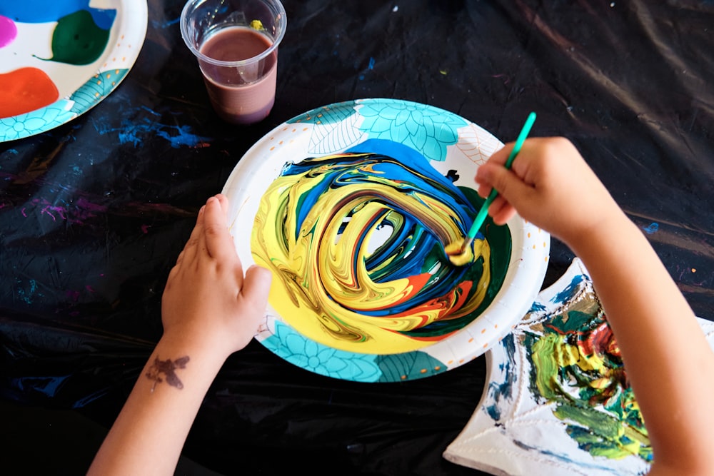 a child is painting on a paper plate