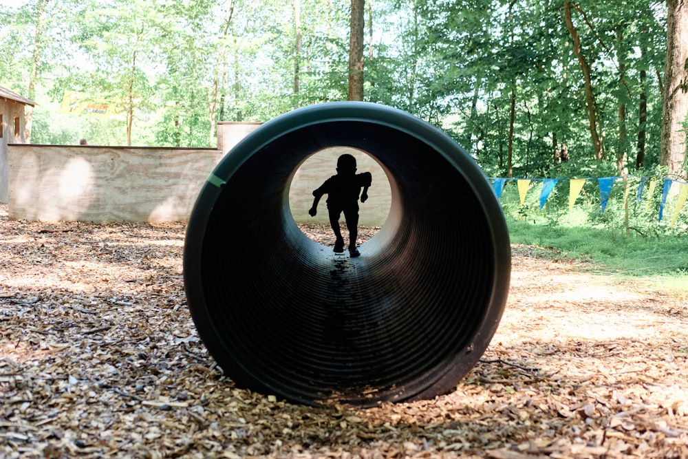 La silhouette d’un enfant est vue à travers le trou d’un pneu