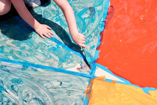 A child’s hands painting a small gegant figure with bright colors on a clean, light table.
