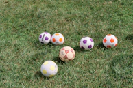 Mini footballs in various vibrant colors arranged in a dynamic pattern on a sports field.