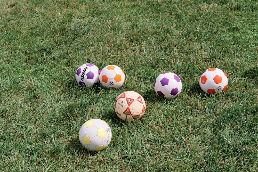 a group of soccer balls sitting on top of a lush green field