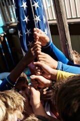 A group of diverse Americans holding an American flag together at a community event.