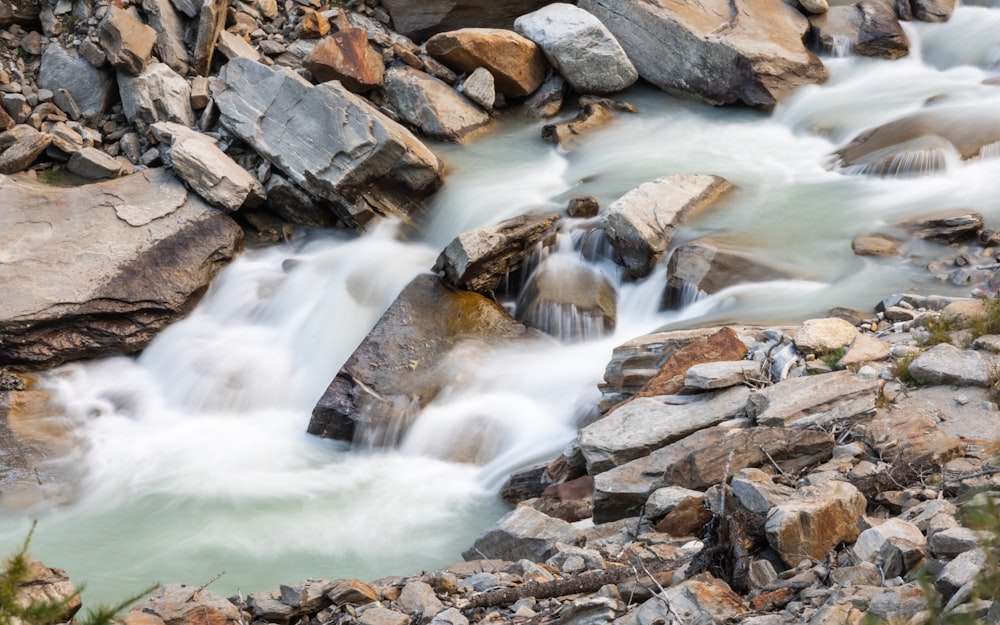 a stream of water running between rocks and grass