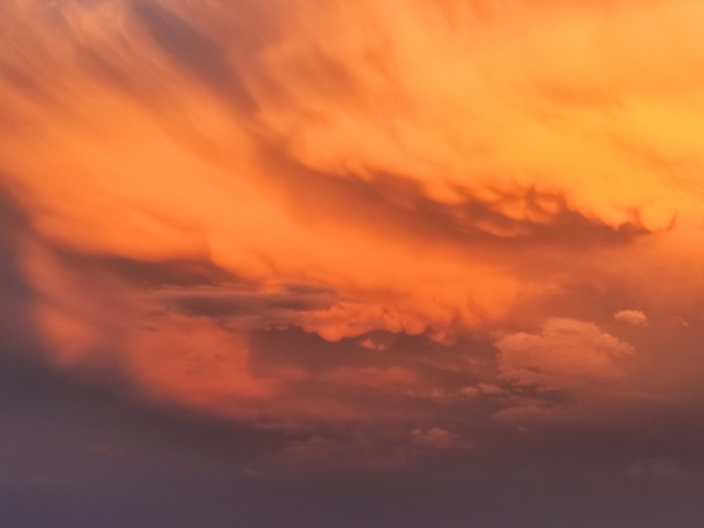 a plane flying through a cloudy sky at sunset