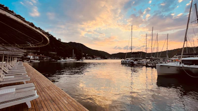 Luxurious floating lounge area on the Marénobre boat at sunset, featuring rich wood textures and navy blue accents.