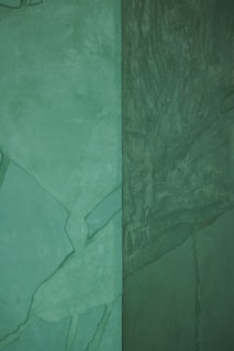 Close-up of freshly painted exterior walls in a soft green shade, showcasing smooth finish.