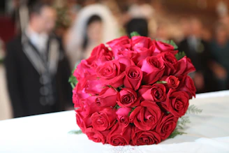 A warm, elegant wedding ceremony with red roses and white decor.