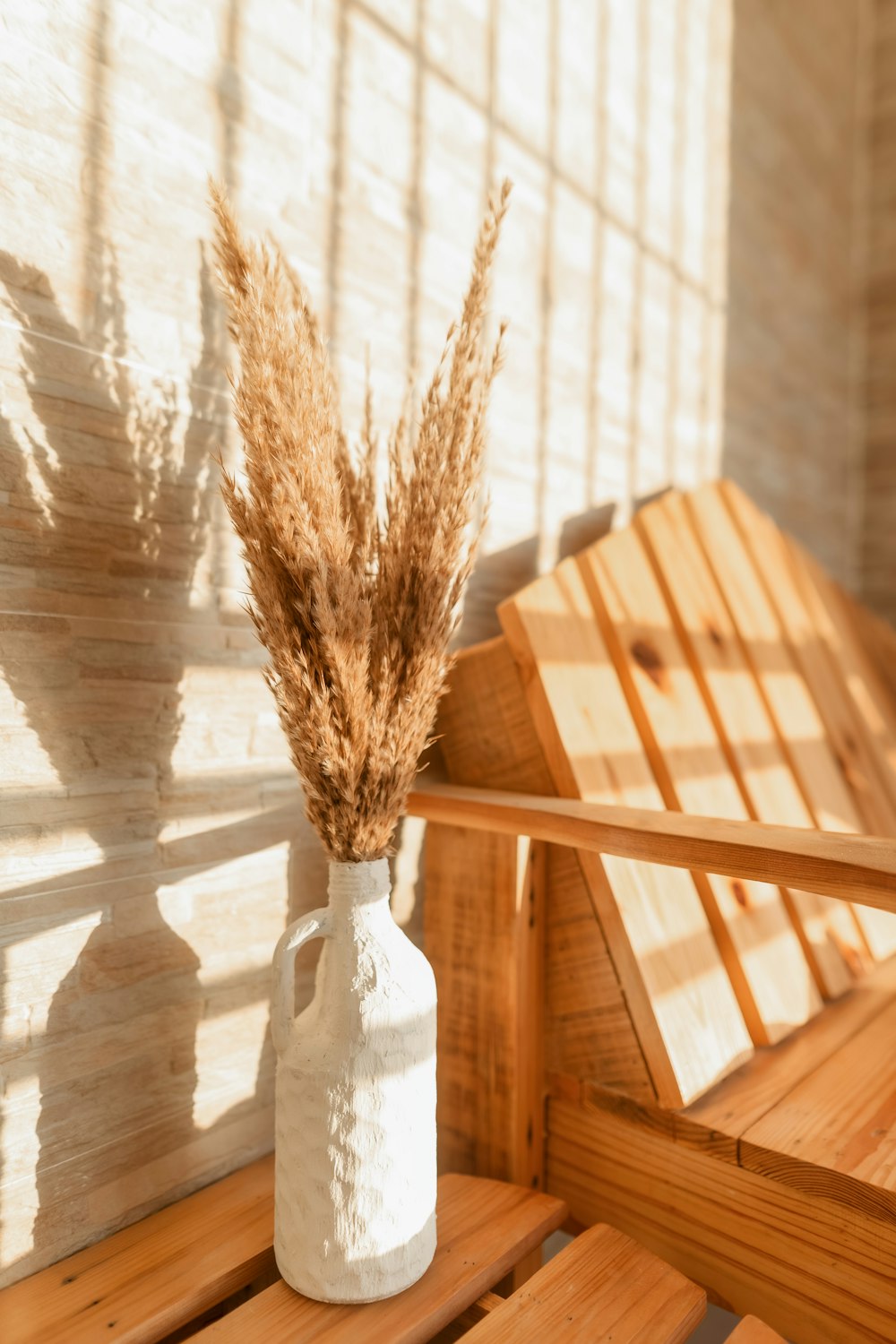 a white vase with some dry grass in it