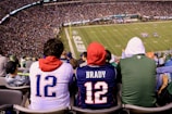 A group of excited fans wearing football jerseys and cheering in the stadium.