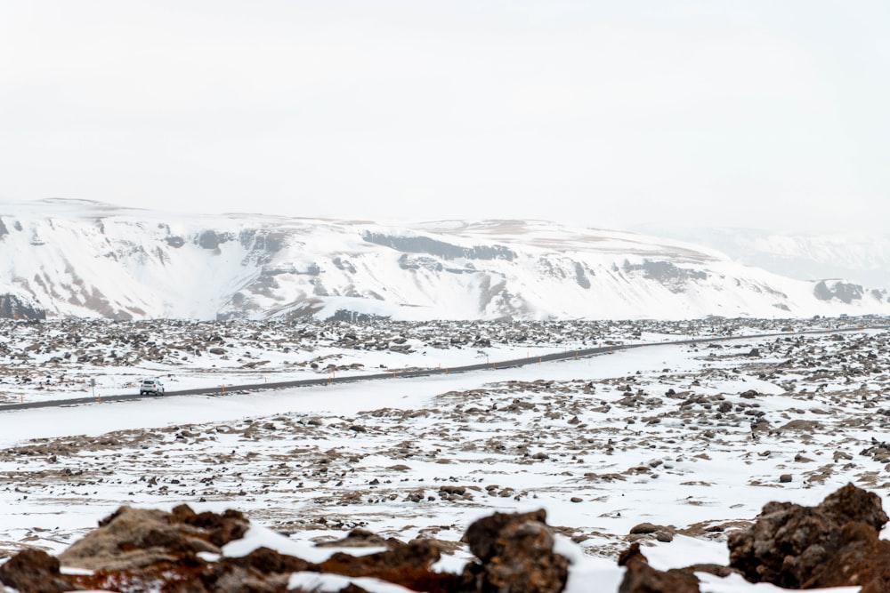 a snow covered landscape with a mountain in the background