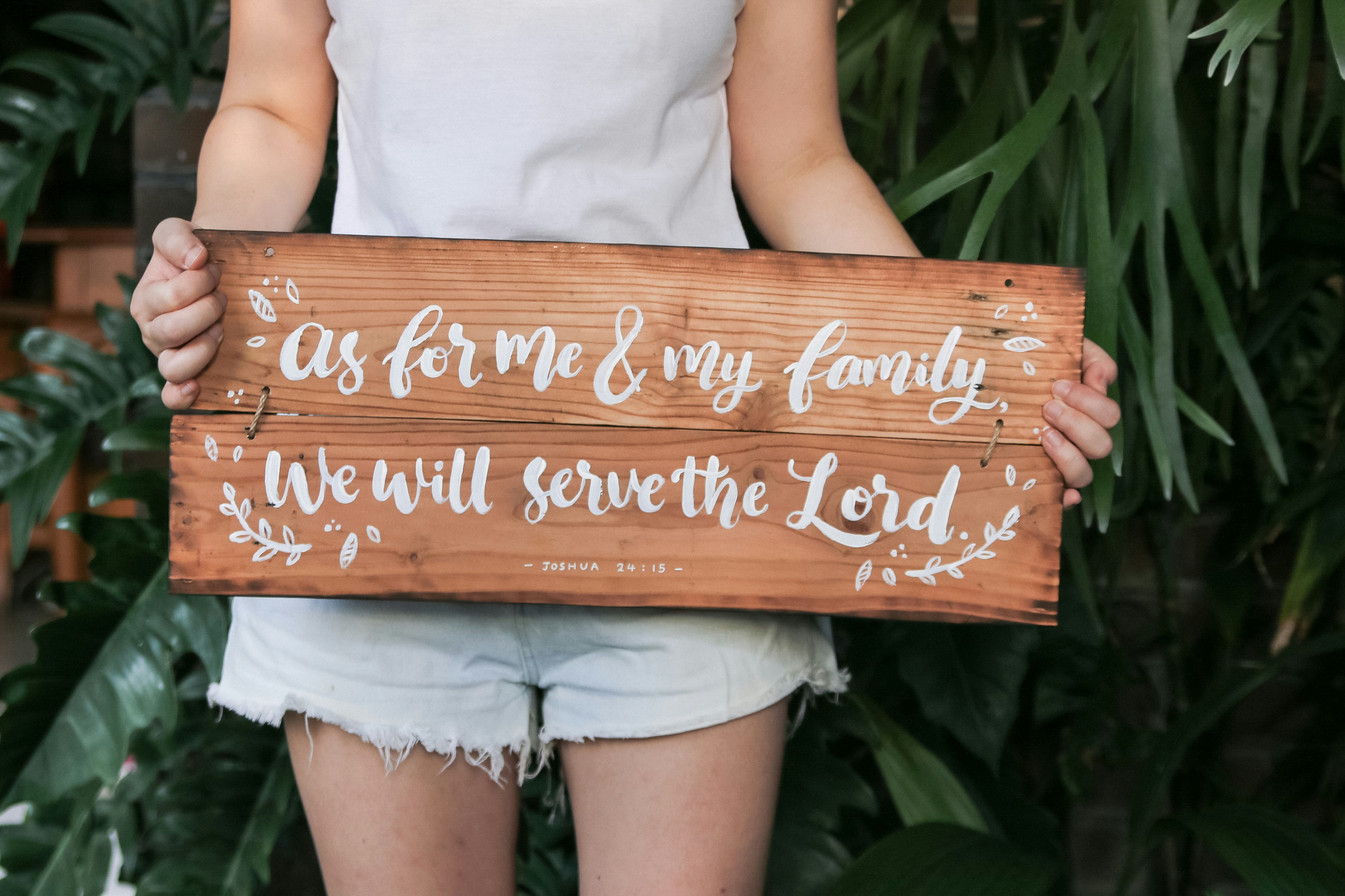 Una mujer sosteniendo un cartel de madera que dice que en cuanto a mí y mi familia lo haremos.
