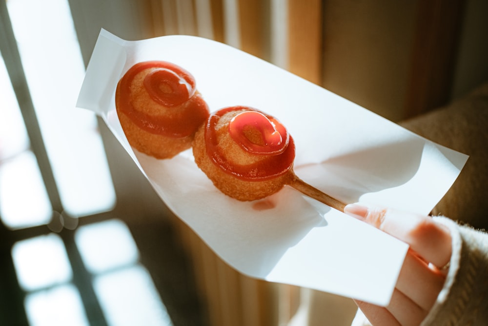 a person holding a piece of paper with two donuts on it