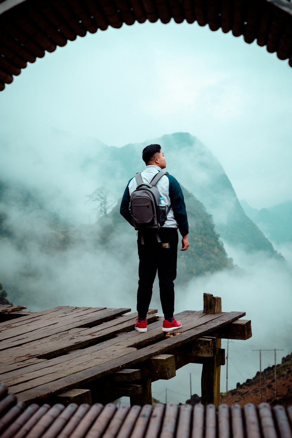 a man with a backpack standing on a bridge