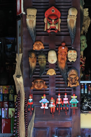 Display of colorful masks inspired by Barranquilla's carnival on wooden shelves.
