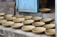 Ceramic bowls and vessels arranged on a rustic table surrounded by Andean mountain views at golden hour.