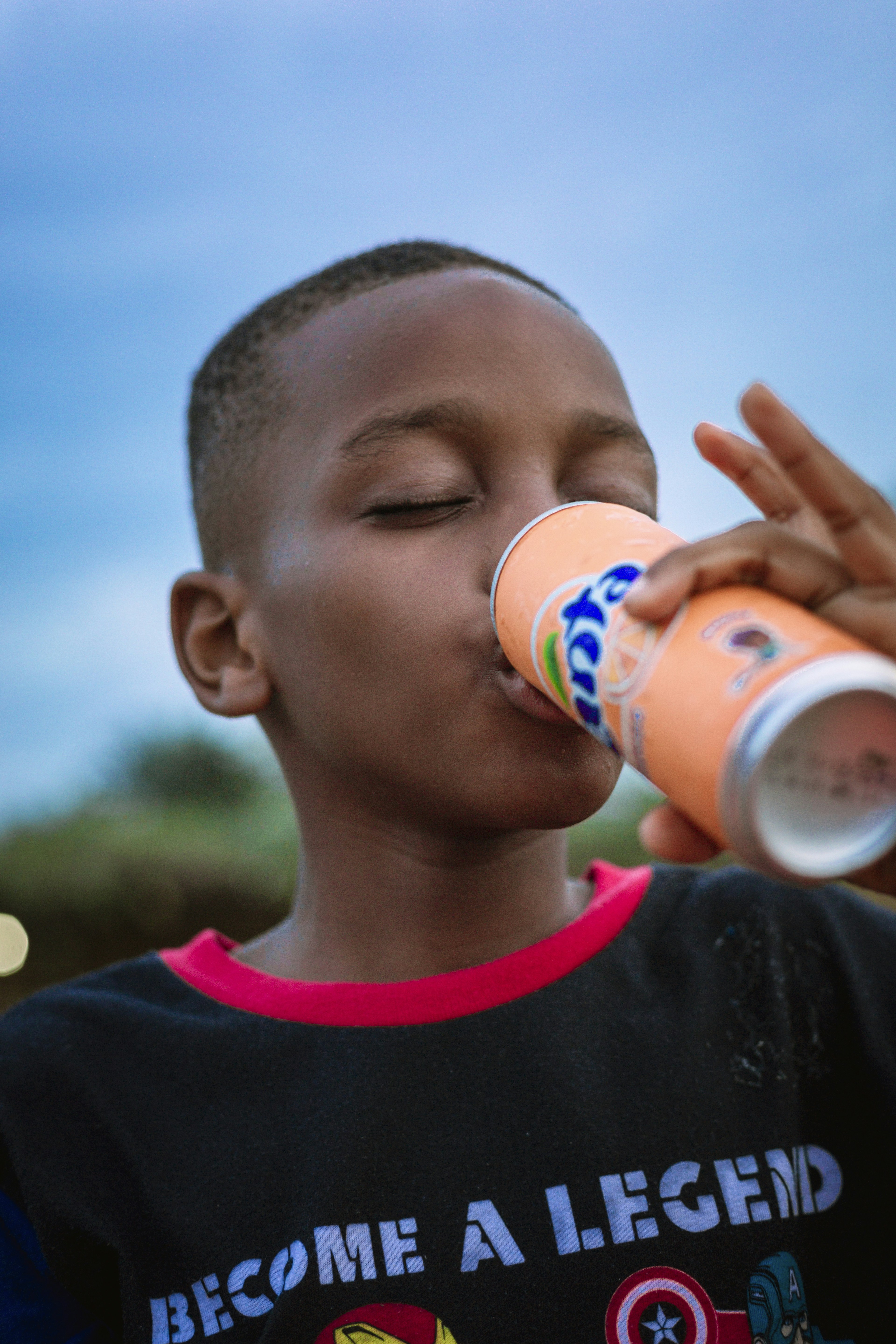 A young boy drinking a drink from a bottle photo Free Portrait Image
