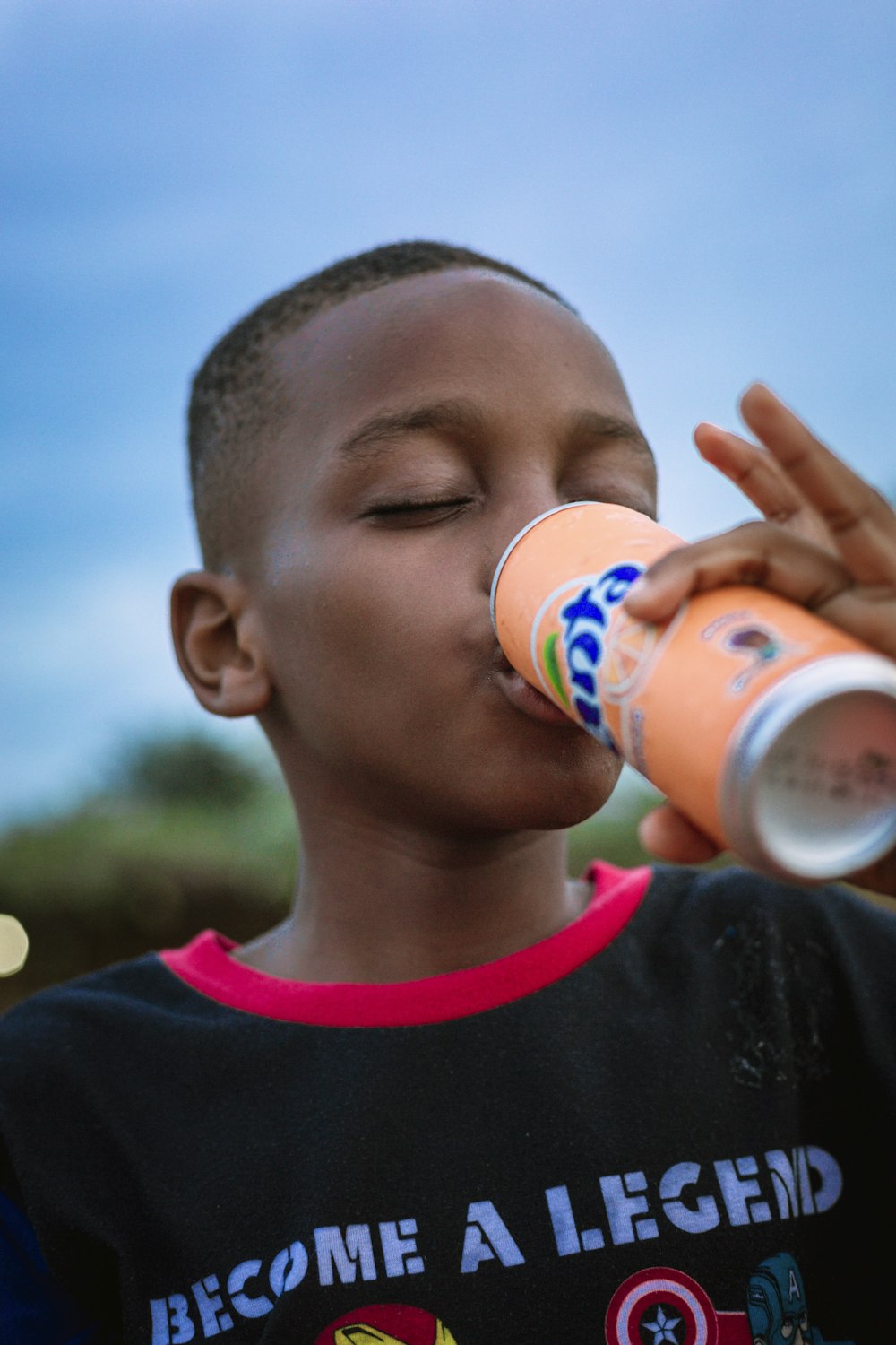 a young boy drinking a drink from a bottle